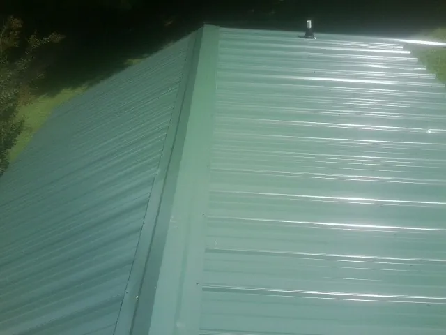 New green metal panels meeting at the ridge of a roof — Flat Roof Repair work by our crew in Oakland