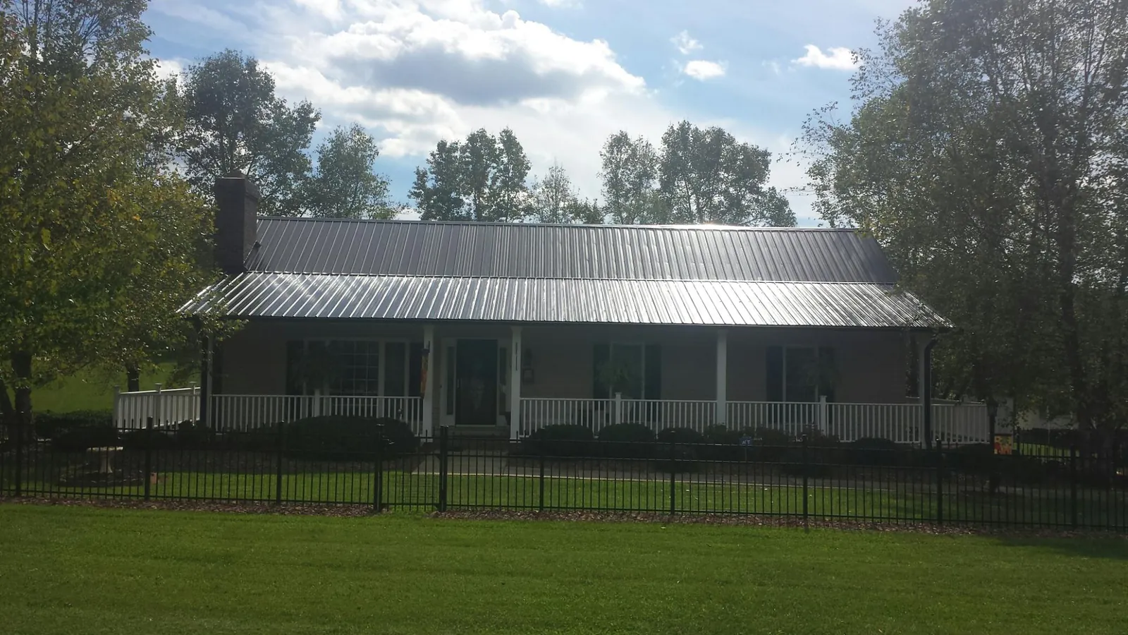 Gray metal roof on a brick ranch with a full width front porch — Gutter Guard Installation work by our crew in Oakland